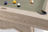 Close-up of a wooden pool table showing the light oak frame, green felt surface, and several billiard balls on a white background.