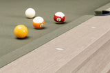 Close-up of a pool table corner with four billiard balls on a green felt surface and a light wood grain rail.