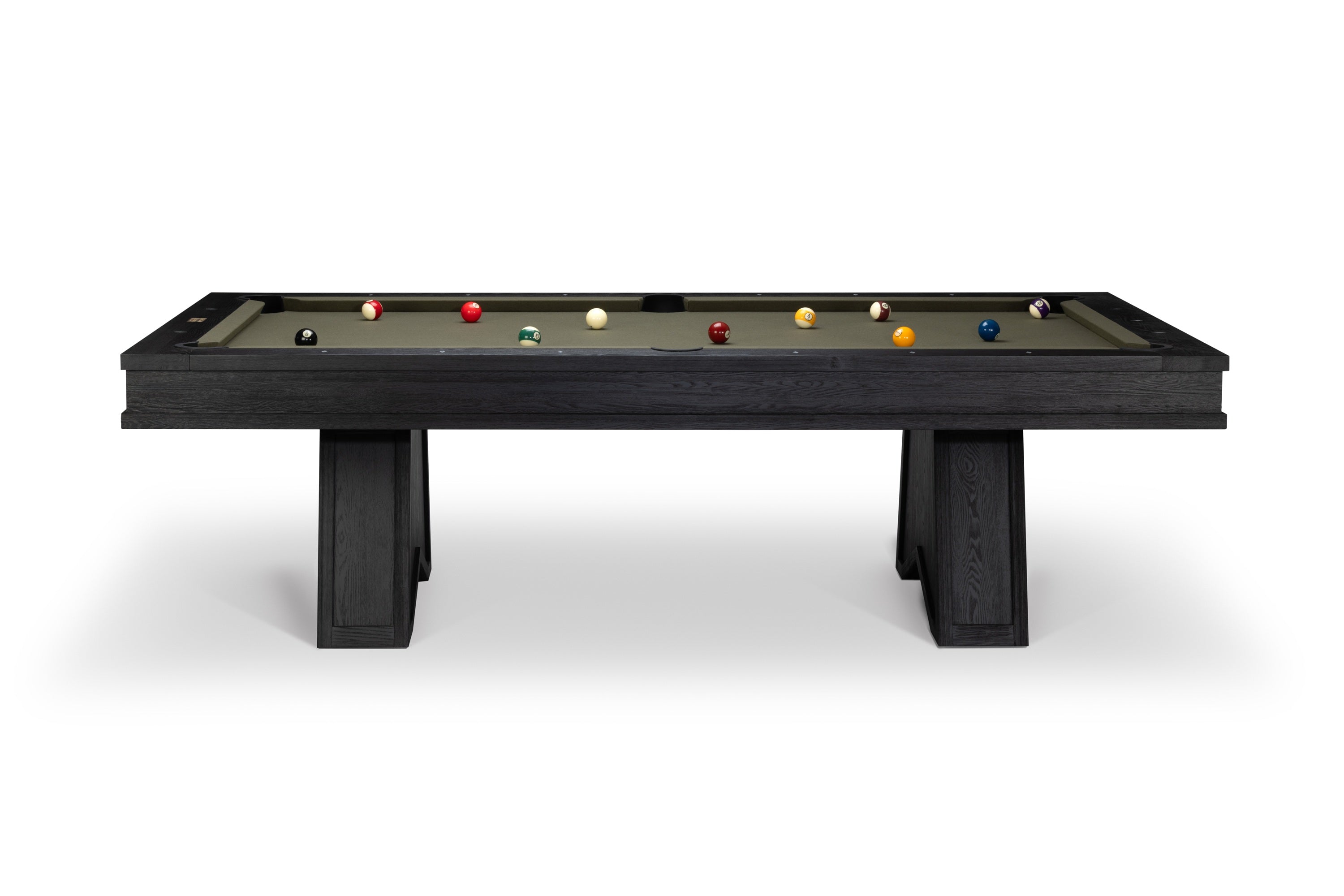 A modern pool table with a dark charcoal wood frame and legs, featuring a green felt surface with various billiard balls arranged on it, set against a plain white background.