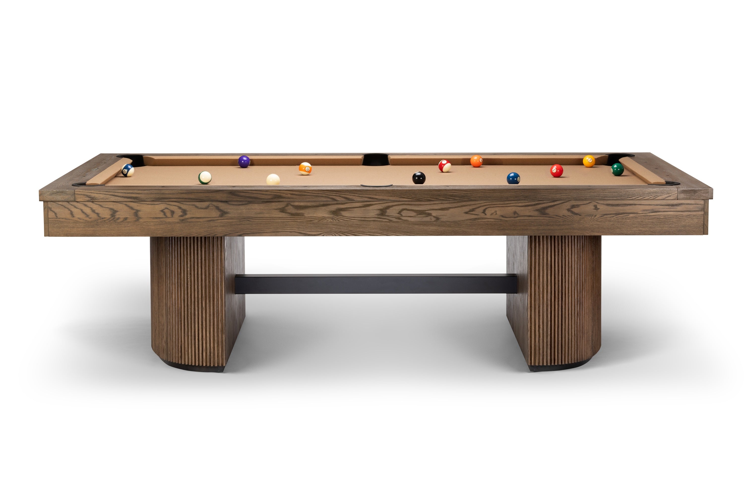 A modern pool table with a medium brown wood grain finish, featuring a light tan felt playing surface, a black metal support beam in the center, and colorful billiard balls arranged on the table, set against a plain white background.